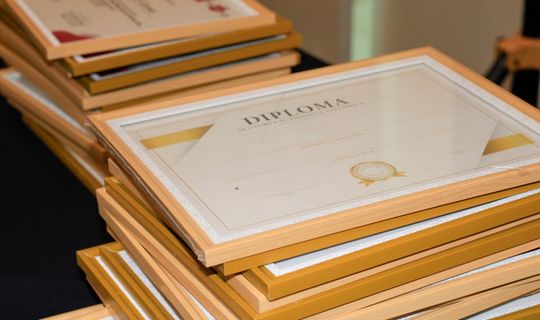 A stack of elegant framed diplomas prepared for an academic ceremony.